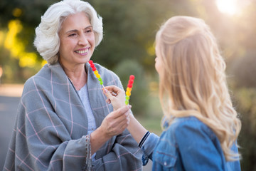 Two happy smiling women showing each other lollypops.