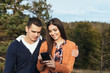 © hedgehog94 - Young couple enjoying together in nature and looking for travel destinations on cell phone.