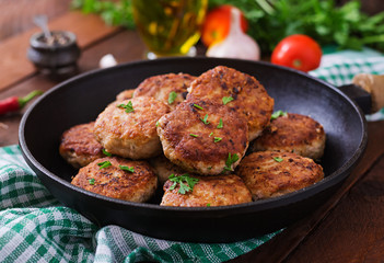 Juicy delicious meat cutlets in pan on a wooden table.