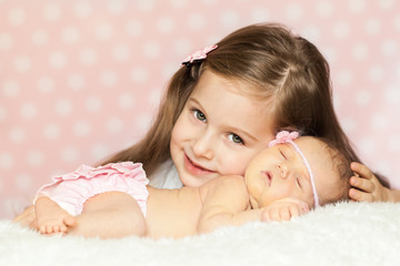 cute little girl with a sleeping newborn sister