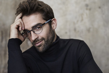 Wall Mural - Thoughtful man in black sweater and glasses, portrait