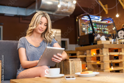 Young Cute Blonde Girl With Wavy Hair Read Something On Her Tablet