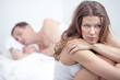 © pressmaster - Dissatisfied woman sitting by bed where her husband is sleeping