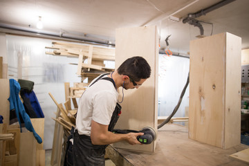 man polishes boards. carpenter with sander