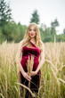 © demchyna - Portrait of a happy pregnant woman in a burgundy dress with long blond hair in tall grass