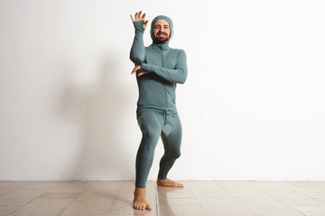 Wall Mural - Happy smiling bearded fitted male wearing snowboarding thermal baselayer suite and posing like a ninja, isolated on white