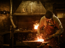 The Blacksmith Forging The Molten Metal On The Anvil In Smithy
