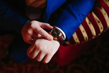 closeup designer watch on businessman hand, he looks on the time and hurrying