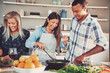 © Flamingo Images - Three friends frying food in pan together
