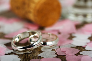 wedding rings on a wooden background with confetti