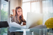 © kokliang1981 - Young business woman using laptop and thinking her building home project plan while sitting at desk on office with drawing pape