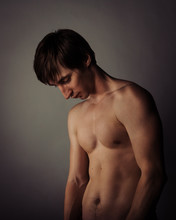 European Young Guy With A Naked Torso And Body In The Studio Looking Down And Sad