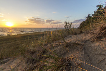 Wall Mural - Summer Beach Sunset Horizon. Sunset on the horizon of a wide sandy beach with a sand dune and dune grass in the foreground. Hoffmaster State Park. Michigan.