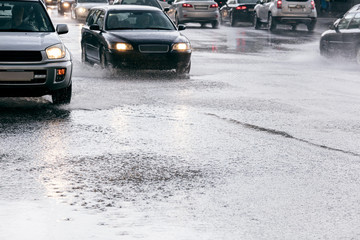 Wall Mural - cars driving on road with water puddles during heavy rain with water splashing from the wheels