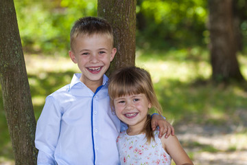 Wall Mural - Portrait of a smiling hugging little girl and boy on a sunny day