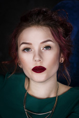 Wall Mural - Young beautiful red-haired caucasian woman with professional makeup in green dress