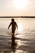 Silhouette Of Young Boy Wading In Water