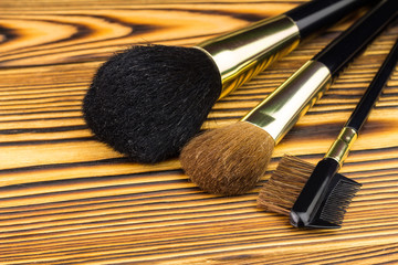 Professional cosmetic brushes for makeup on wooden background.