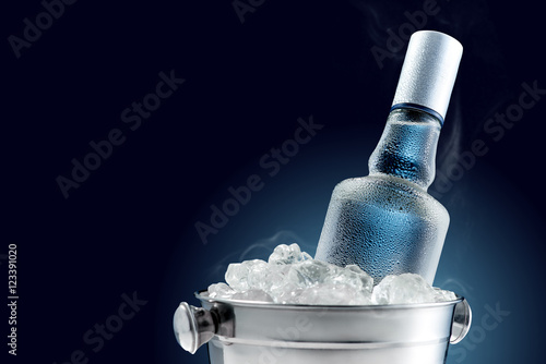 Fotografía Bottle of cold vodka in bucket of ice on dark background