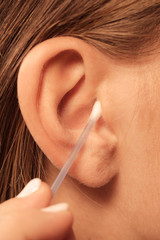 Wall Mural - Woman cleaning ear with cotton swabs closeup