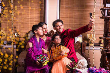 asian indian family taking selfie or self photograph at home with gift boxes on diwali festival. par