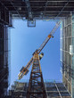 © fStop - Directly below shot of crane and glass building against clear blue sky