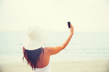 Wall Mural - smiling young woman taking selfie with smartphone