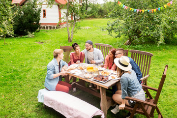 Canvas Print - happy friends having dinner at summer garden party