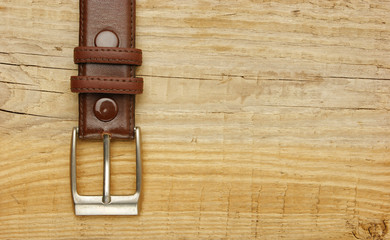 leather belt with a buckle on a wooden board