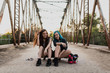 © ADDICTIVE STOCK - Smiling young woman girls sitting on skateboard
