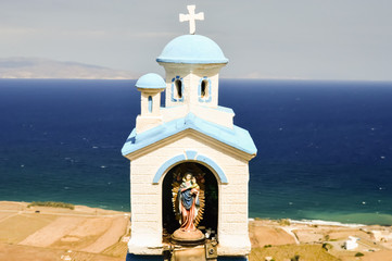 A small statue of the Madonna and Jesus overlooking the sea on t