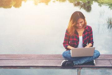 Young happy hipster woman working with her laptop sitting on pie