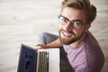 Wall Mural - Smiling man with laptop on the floor