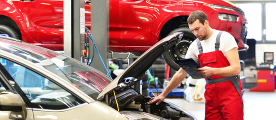 Wall Mural - Kundendienst in einer Autowerkstatt - Mechaniker kontrolliert Fahrzeug