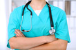 © rogerphoto - Female surgeon doctor is standing with arms crossed at hospital.  Physician  is ready to examine patient