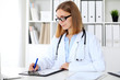 © rogerphoto - Female doctor  writing a medical prescription at clipboard