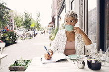 Woman Drinking Coffee At Sidewalk Cafe