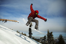 Male Snowboarder Jumping On Snowcapped Mountain Against Sky