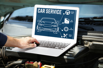 Wall Mural - Mechanic with laptop near car engine. Modern car diagnostic program on screen. Car service concept.