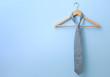 Male tie hanging on the rack, blue background
