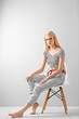 © Africa Studio - Pretty young woman in casual clothes sitting on chair against light background