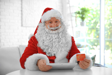 Sticker - Santa Claus with credit card and tablet at home