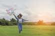 © sunti - A beautiful young woman holding balloons , running along the pas