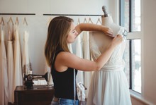 Female Fashion Designer Adjusting The Dress On Mannequin