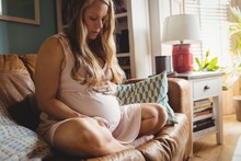 Pregnant Woman Relaxing On Sofa In Living Room