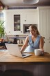 © Wavebreak Media - Pregnant woman using laptop while having coffee in kitchen