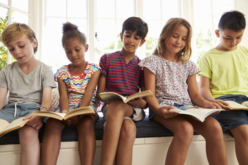 Group Of Multi-Cultural Children Reading On Window Seat