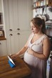 © Wavebreak Media - Pregnant woman using digital tablet in kitchen