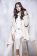 © dorriss - Beautiful woman in a sweater with a hood sitting on a chair