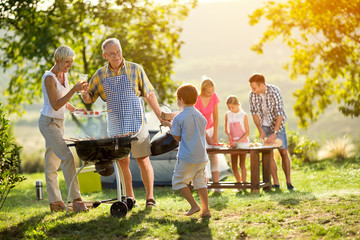 grandson helps grandparents to make a barbecue.